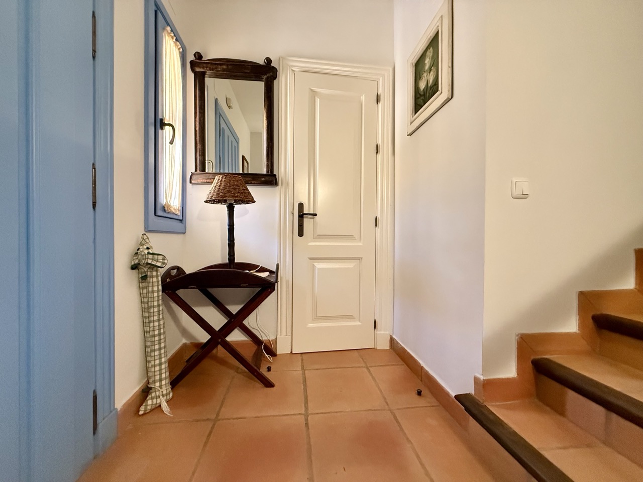 Entrance hallway with staircase, console table and terracotta flooring