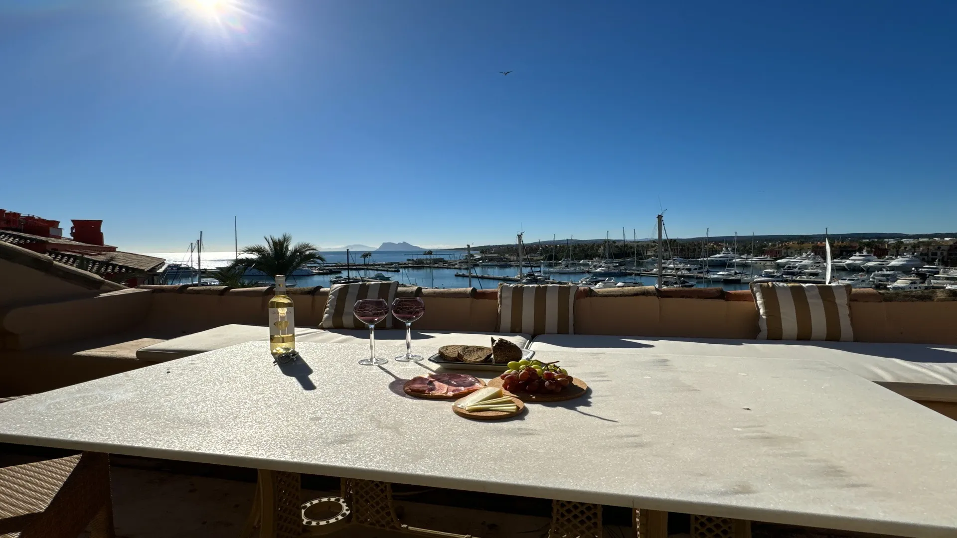 Terraza soleada con tumbonas y vistas panorámicas al puerto deportivo