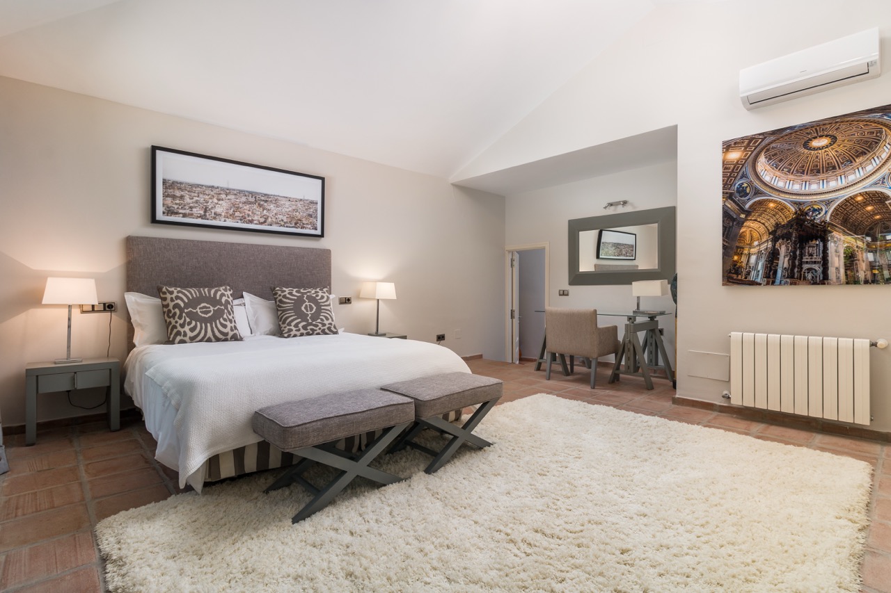 Dormitorio con cama doble, decoración neutra y luz natural suave
