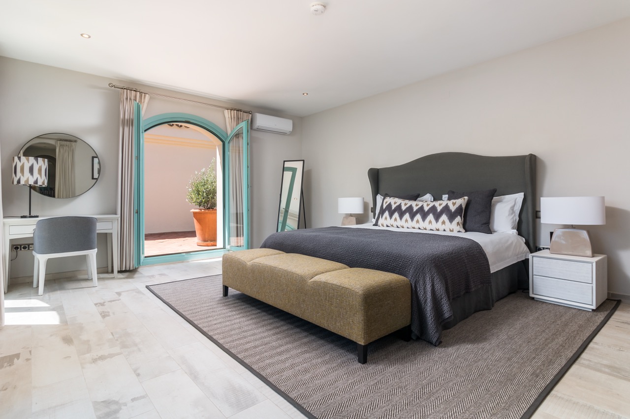 Dormitorio con cama doble, puerta en arco y decoración neutra