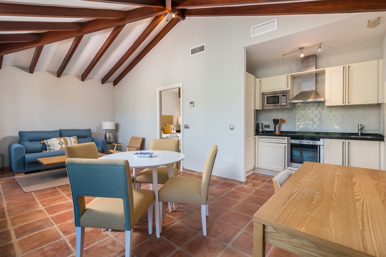 Salón comedor con vigas de madera vistas y acceso a la cocina