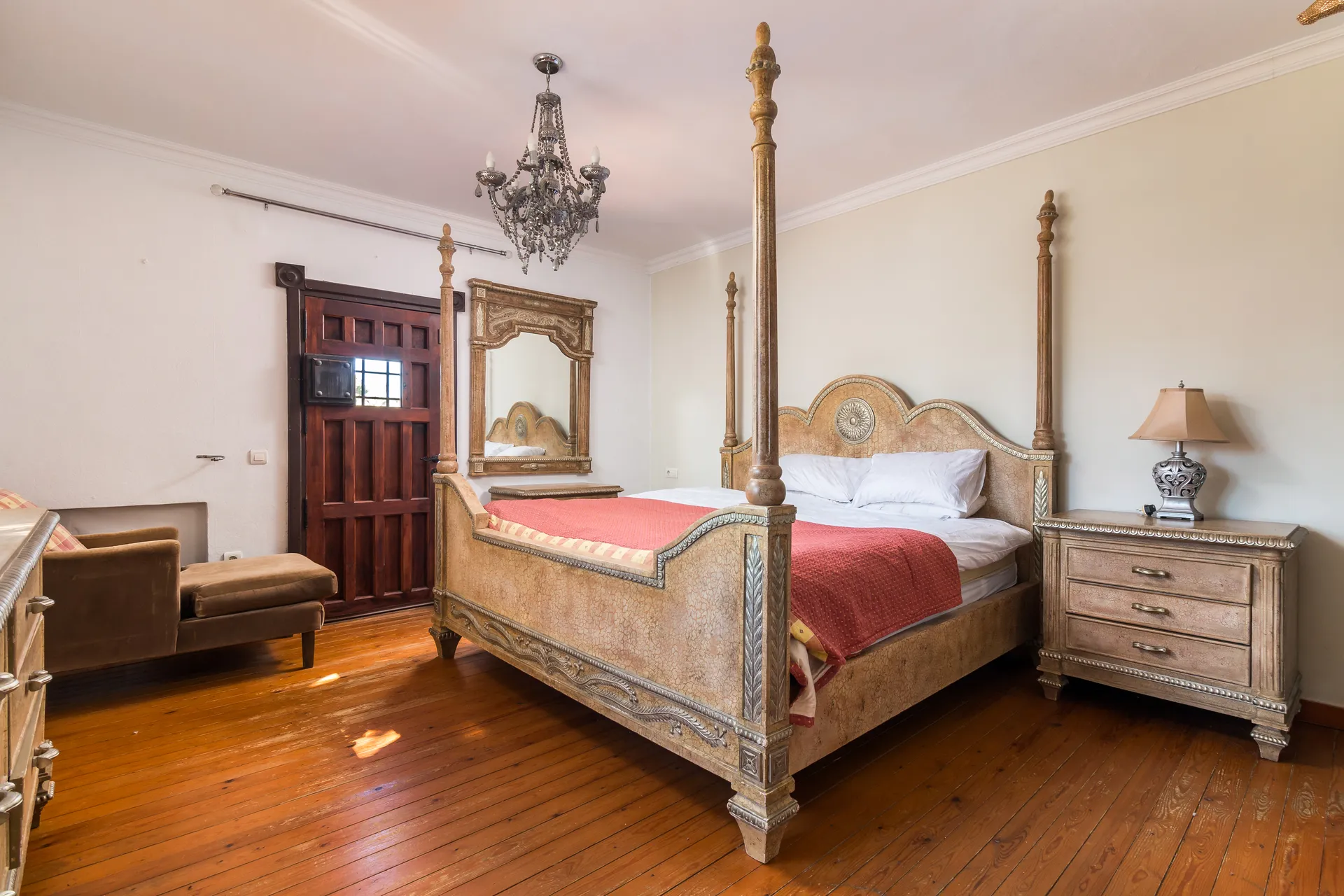 Spacious bedroom with four-poster bed, chandelier and wooden flooring