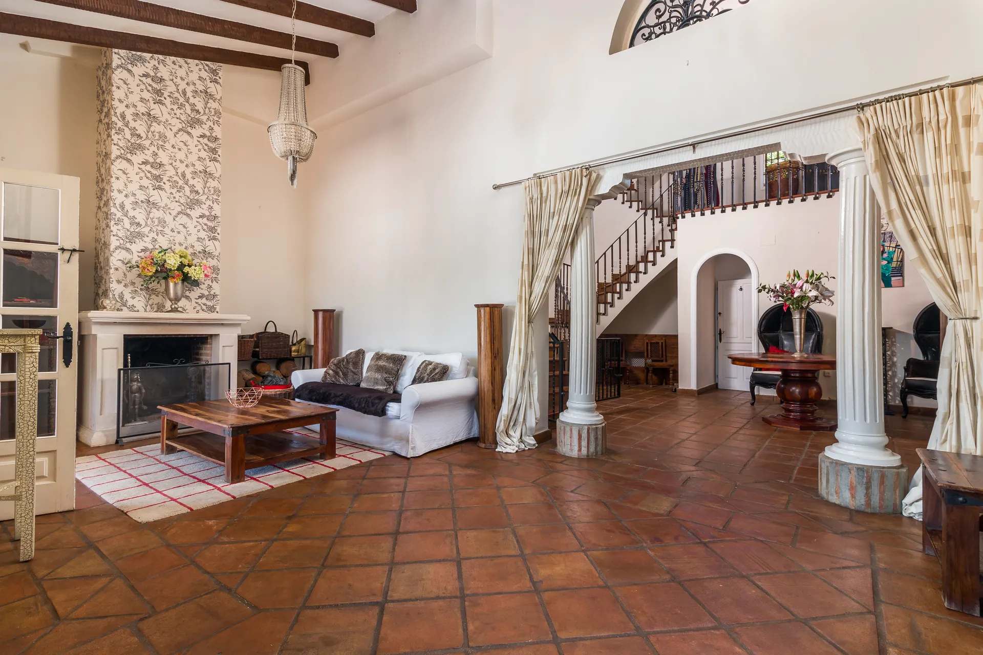 Living room with fireplace, terracotta floors, arches and exposed wooden beams