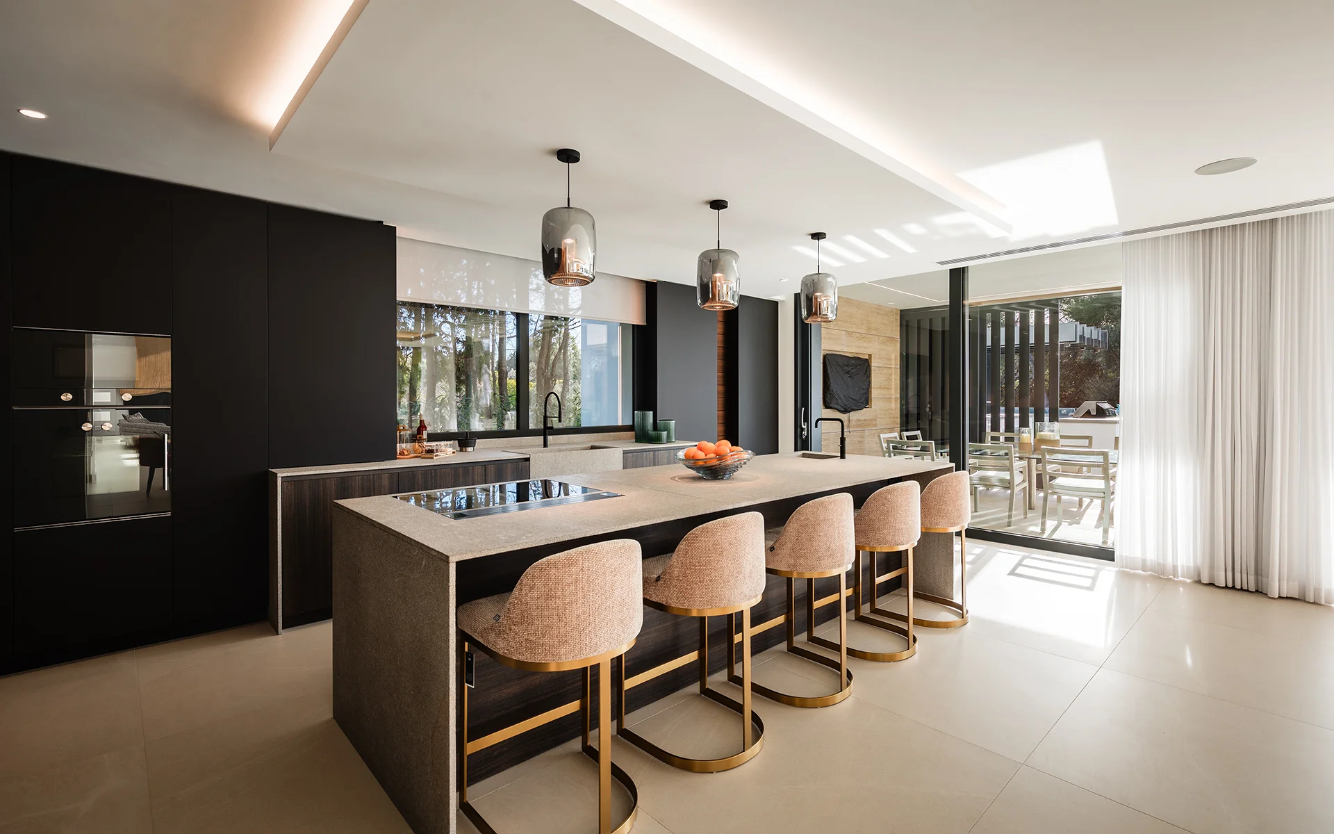 Cocina moderna con isla con taburetes, muebles oscuros y distribución diáfana