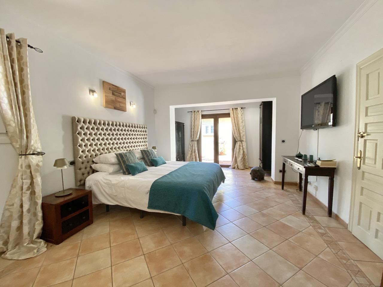 Dormitorio principal con cama doble, suelo de madera y luz natural