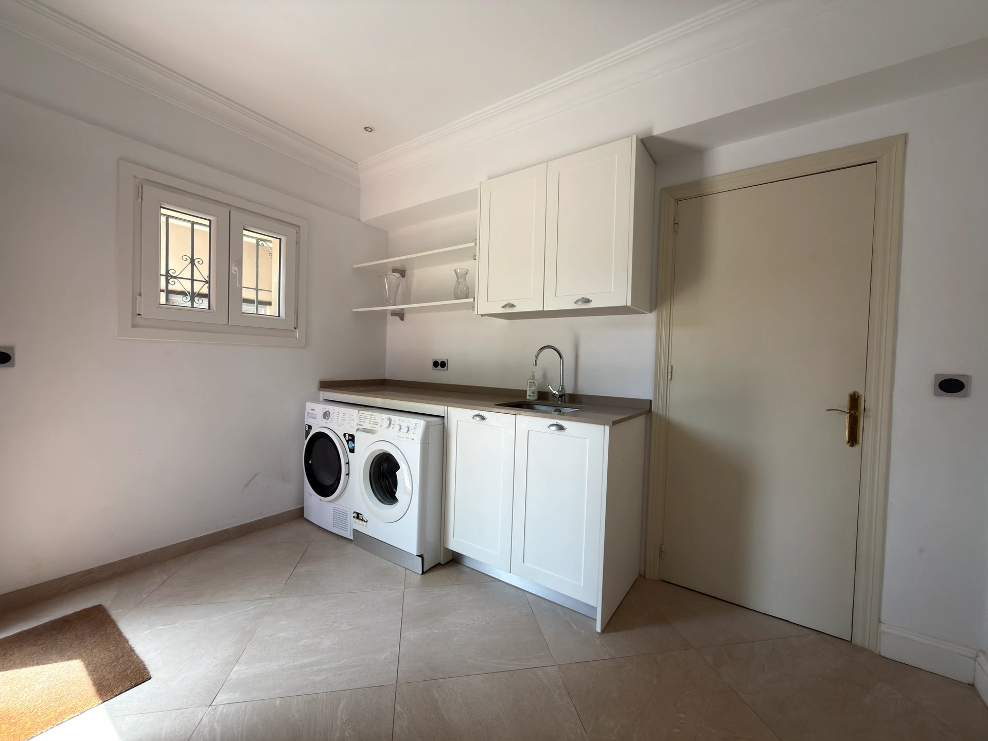 Utility room with washing machine, sink and white cabinetry