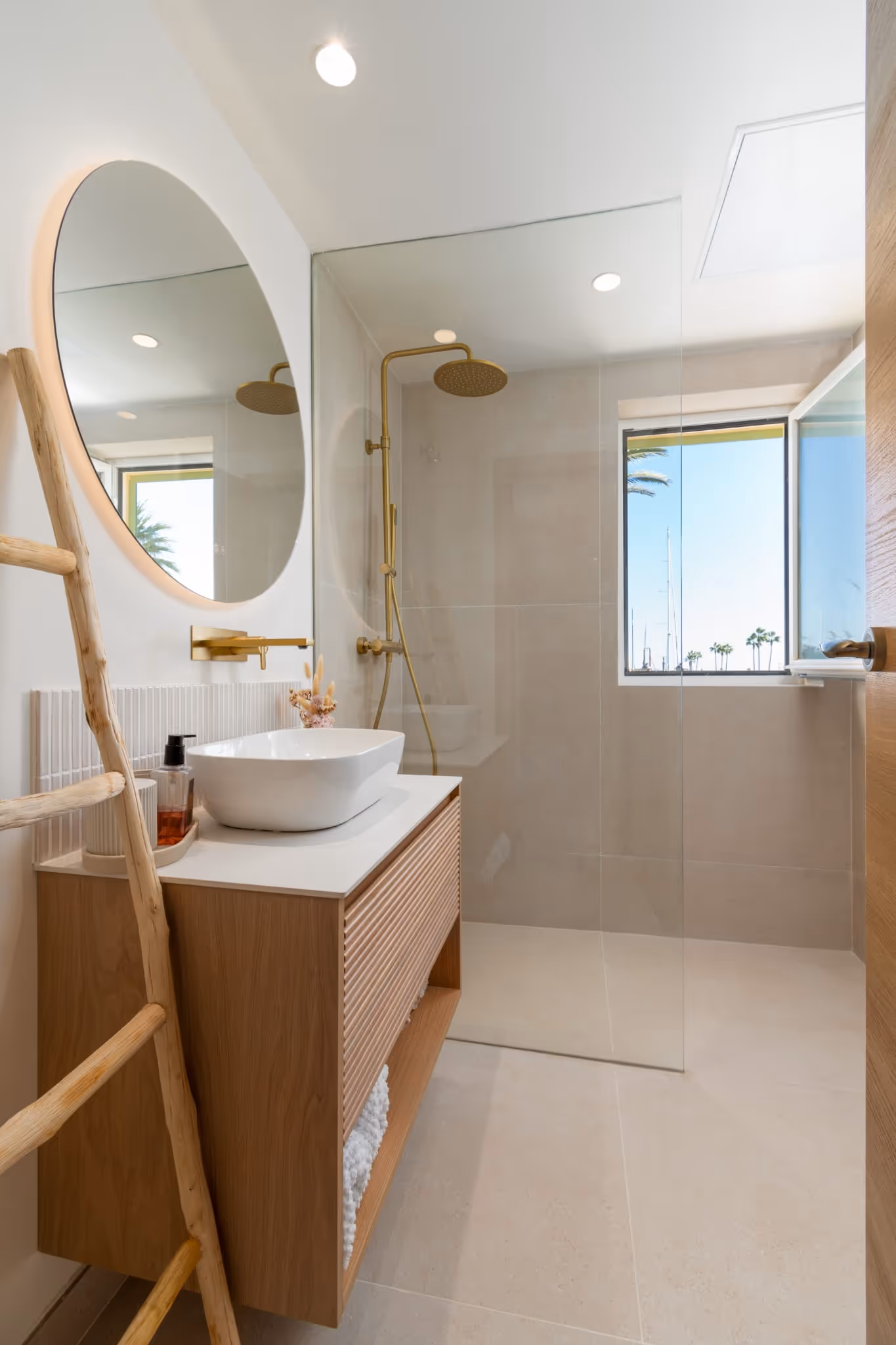 Bathroom with round mirror, vanity unit and window