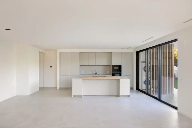 Open-plan kitchen with white island and floor-to-ceiling glass doors