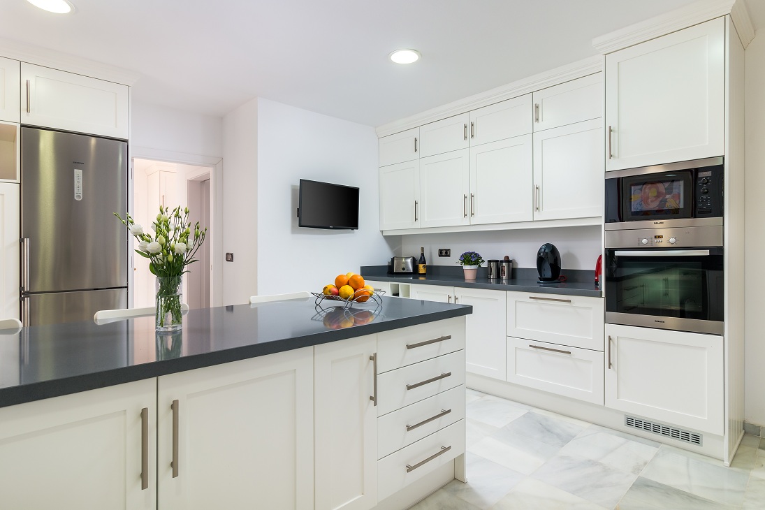 Kitchen with white cabinetry, island and built-in appliances