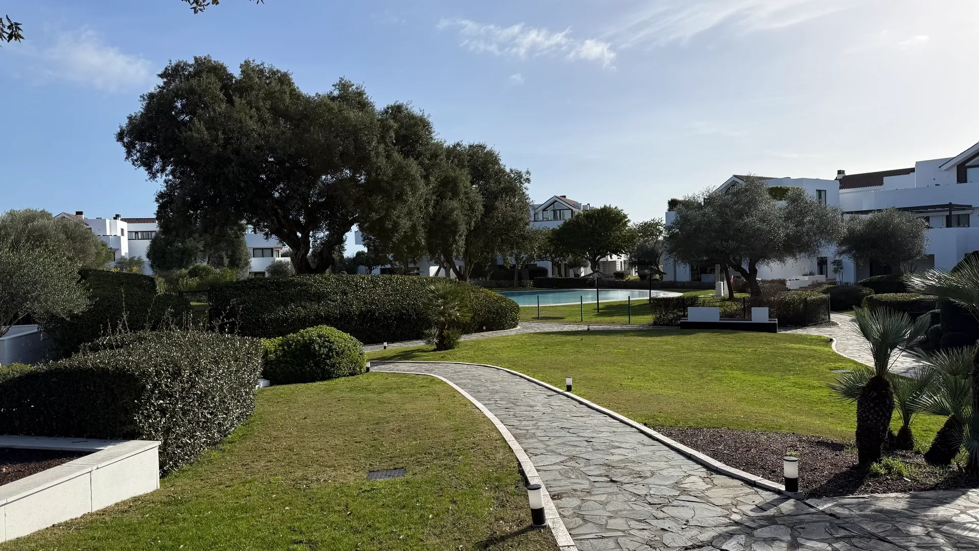 Zona de jardín con césped, camino y vegetación madura