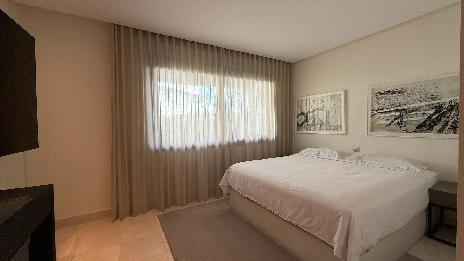 Dormitorio con cama tapizada, decoración neutra y luz natural suave