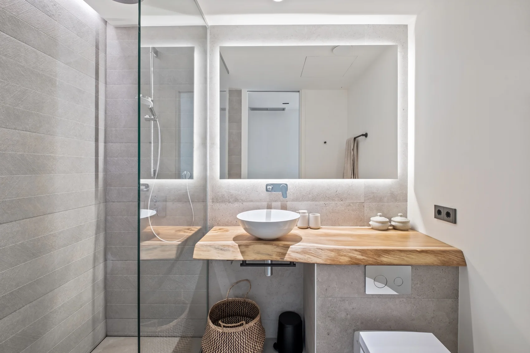 Baño en suite con ducha acristalada, espejo retroiluminado y encimera de madera