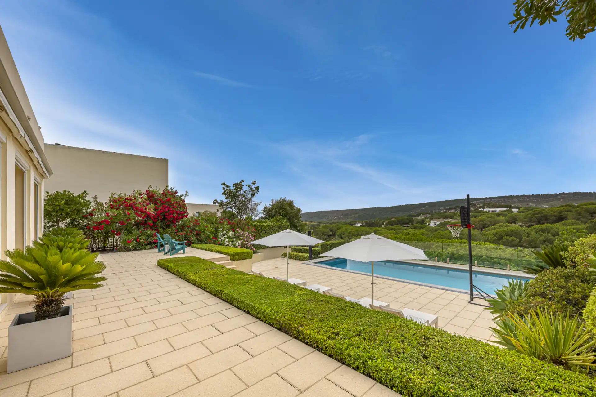 Pool terrace with sun loungers, flowering oleanders and views over the hills