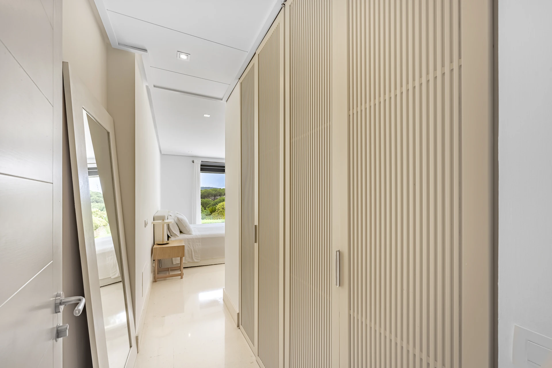 Dressing area with slatted fitted wardrobes leading to the bedroom