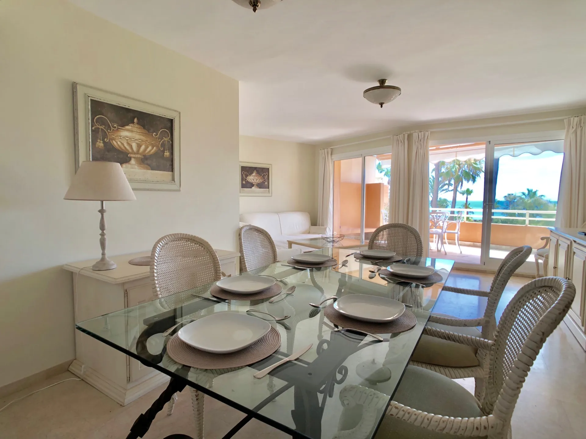 Comedor con mesa de cristal, sillas y acceso a la terraza