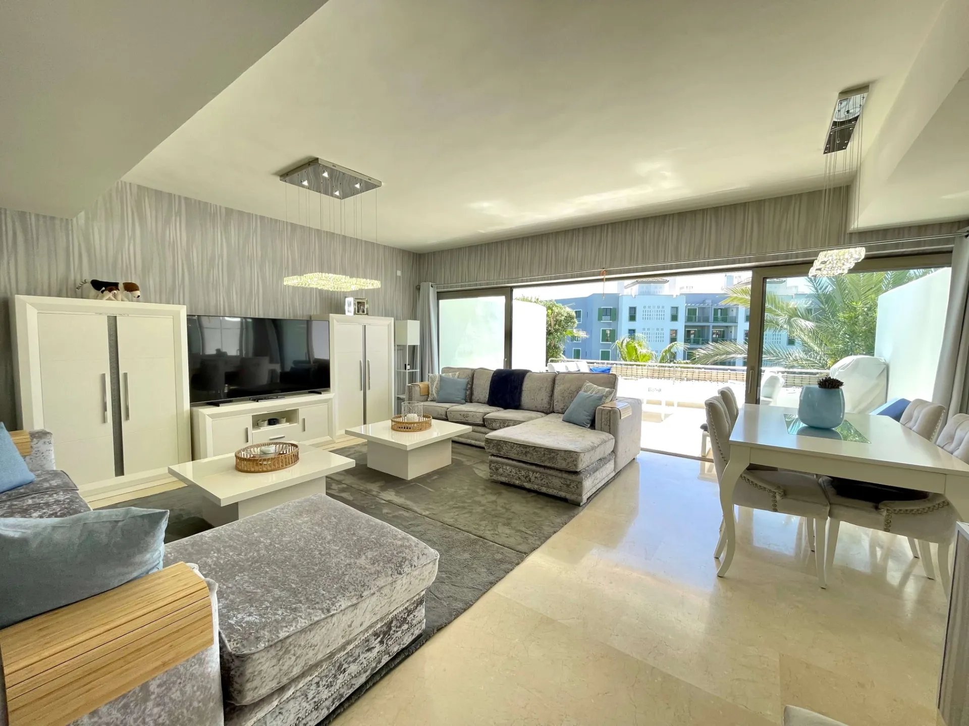 Salón diáfano con sofás, zona de televisión y puertas a la terraza