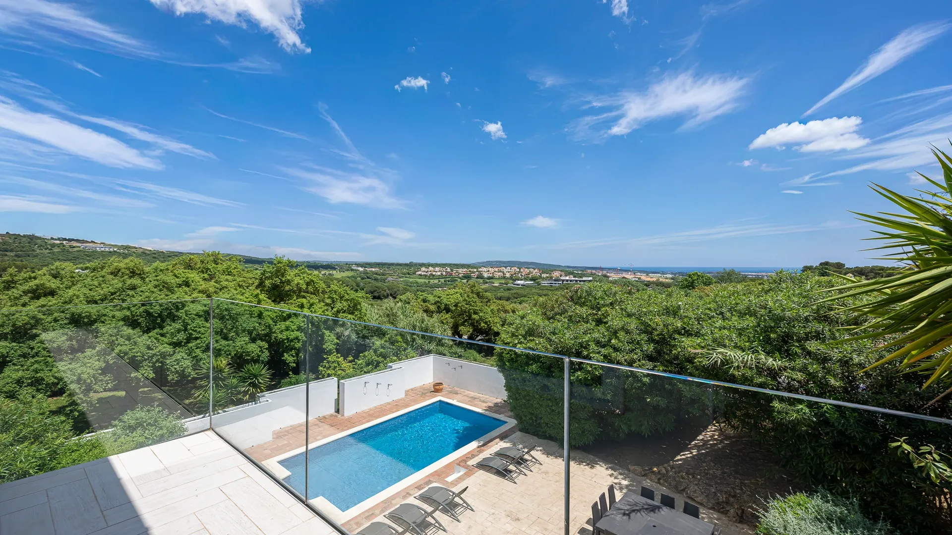 Vista de la piscina y las colinas arboladas desde la terraza de la villa