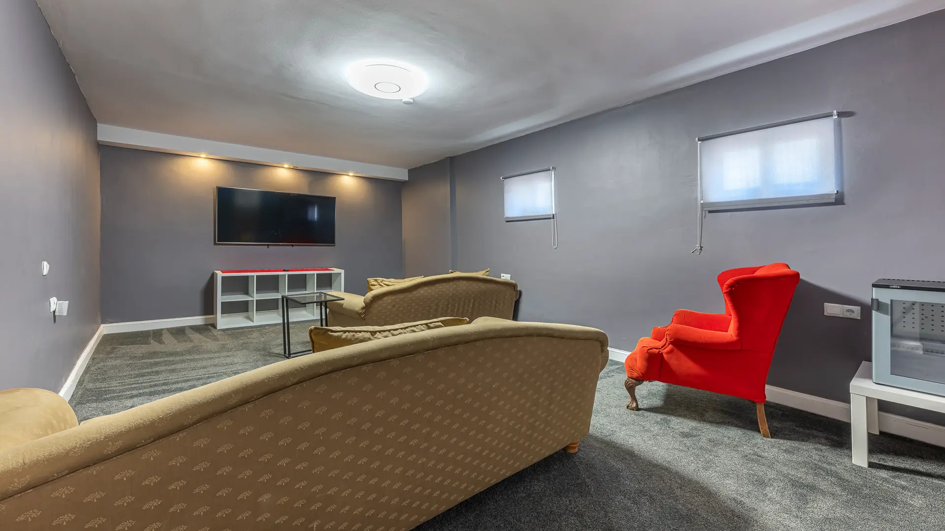Sala de cine con pantalla grande, sofá y sillón rojo