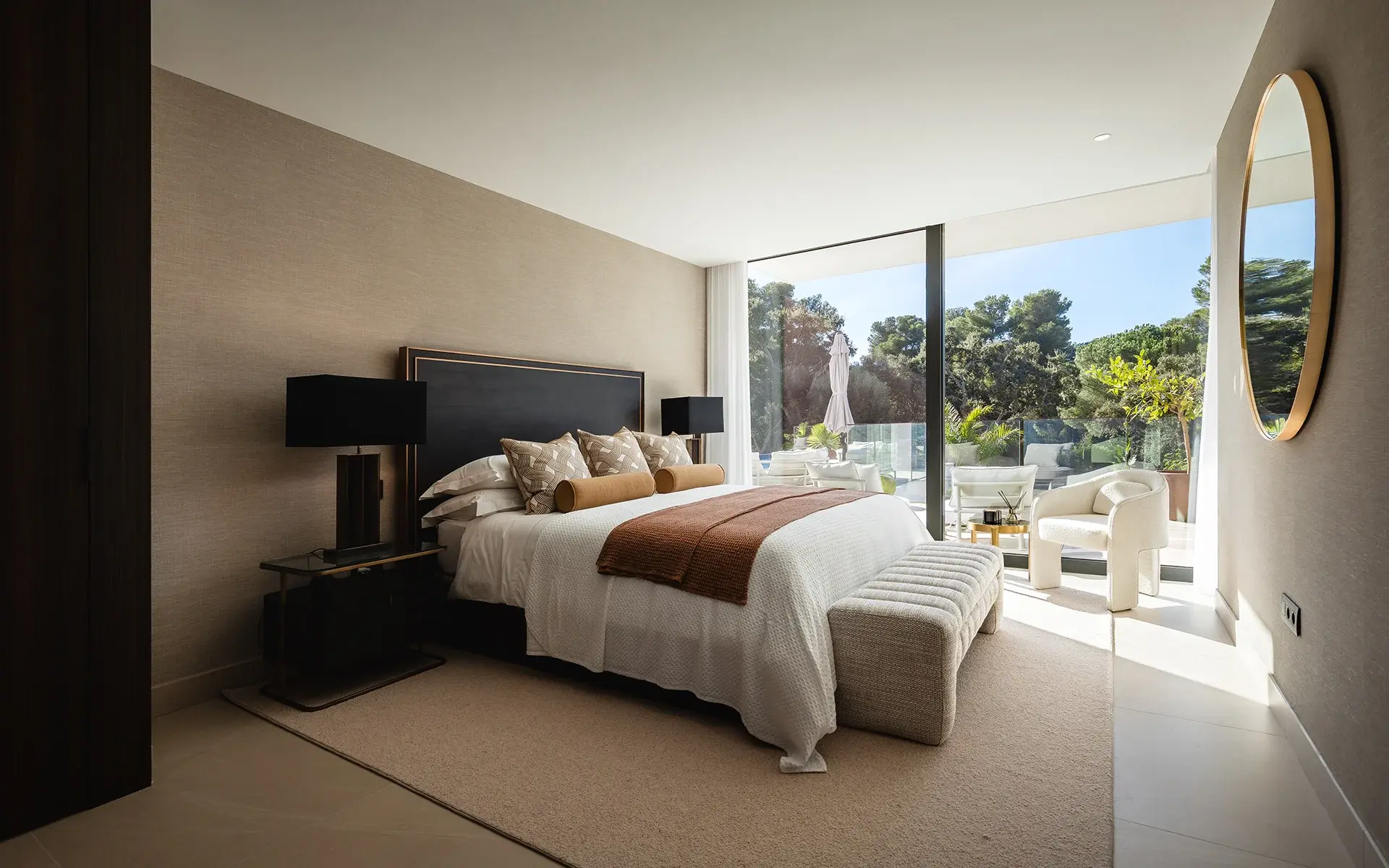 Dormitorio con ventanas grandes, decoración neutra y vistas al jardín