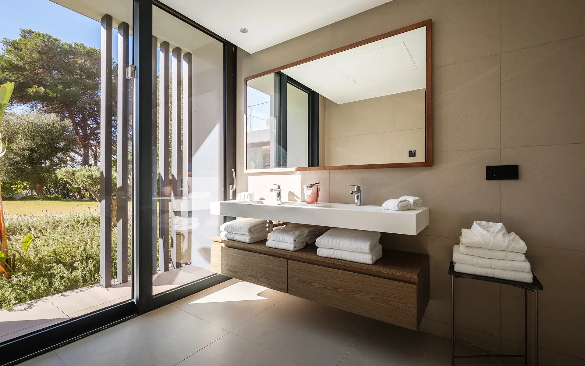 Baño con doble lavabo y ventanales de suelo a techo al jardín