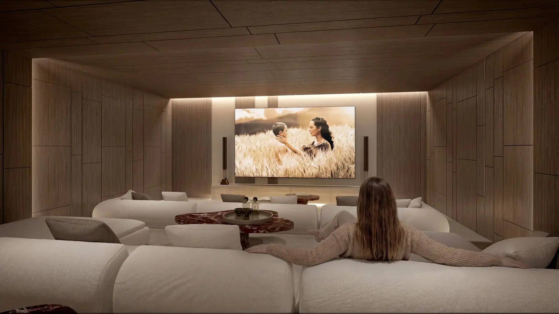 Sala de cine privada con amplio sofá y pantalla en la pared