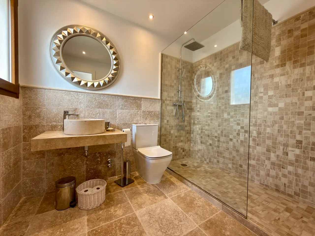 Bathroom with wooden vanity, round mirror and tiled walls