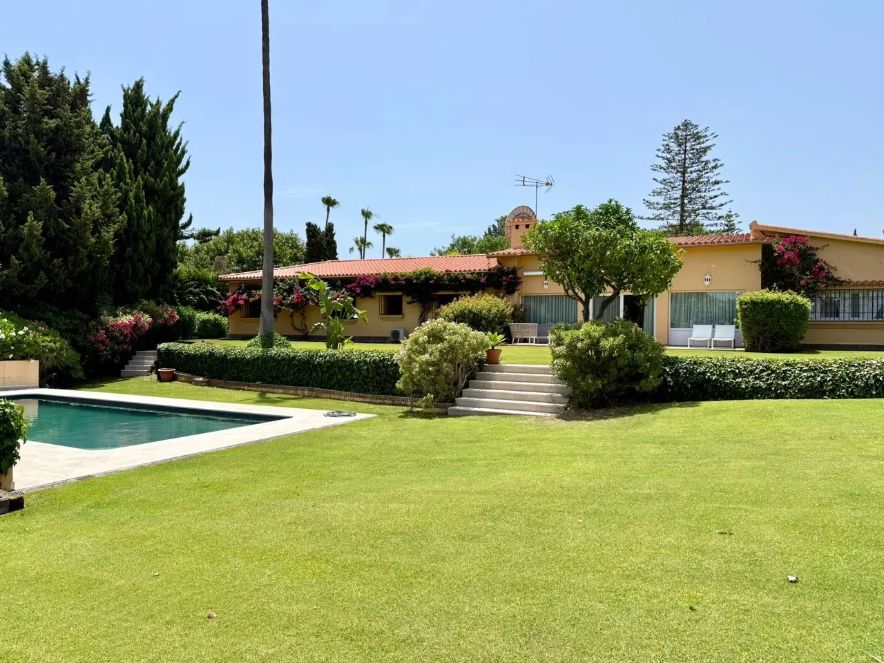Jardín de Villa Carina con piscina, césped y exterior de la villa de una sola planta