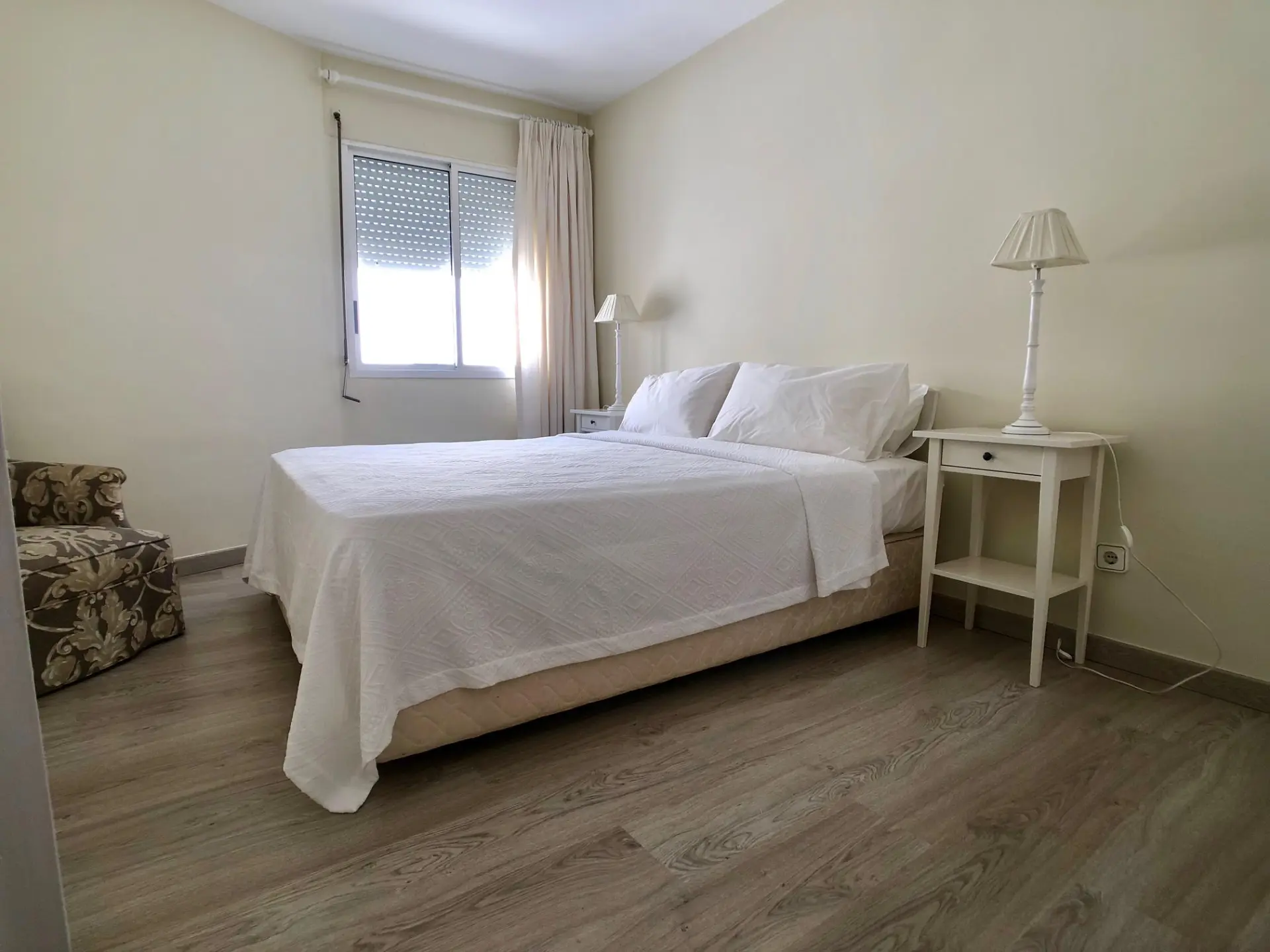 Dormitorio con cama doble, suelo de madera y ventana