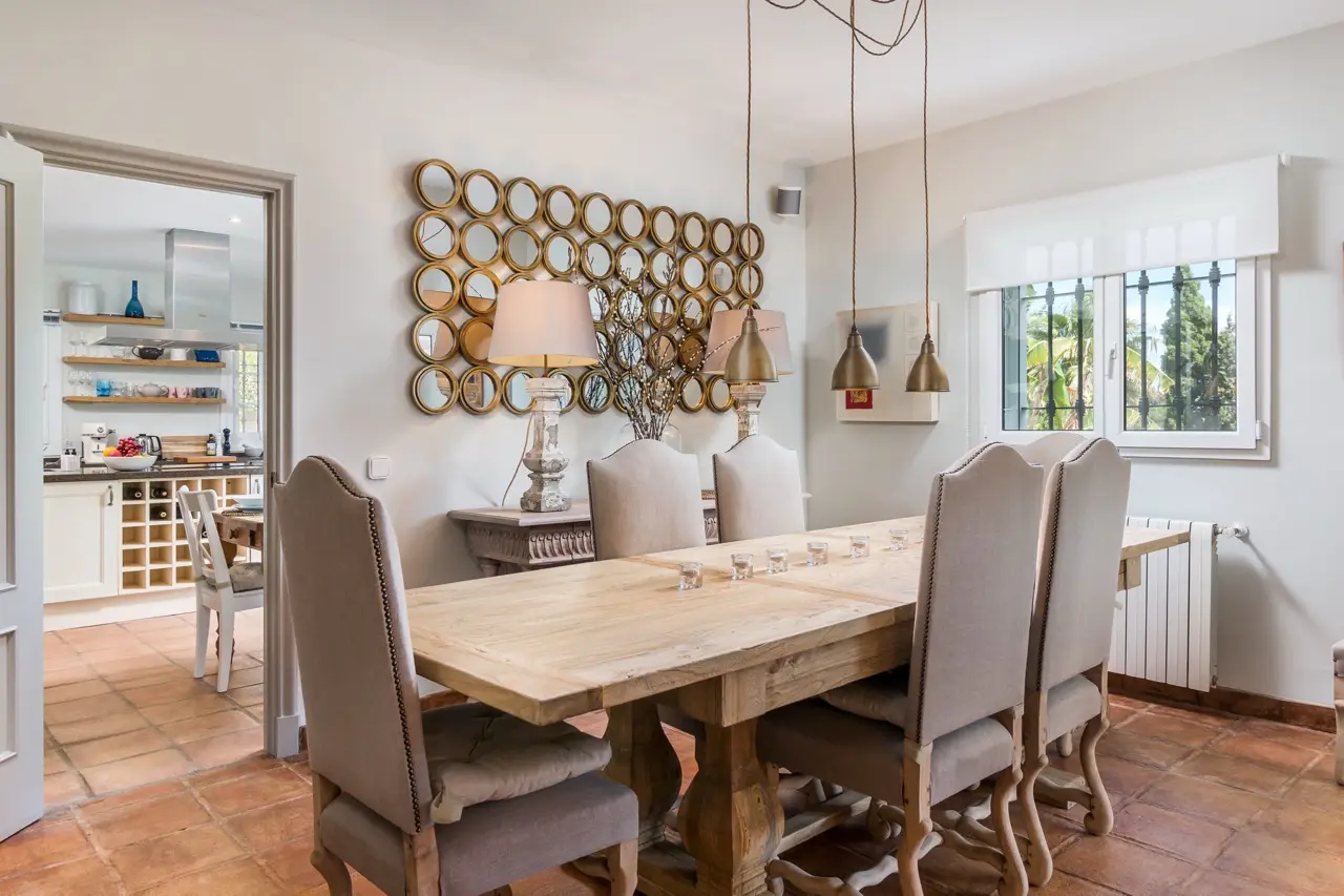 Dining area with long table, upholstered chairs and garden-facing windows