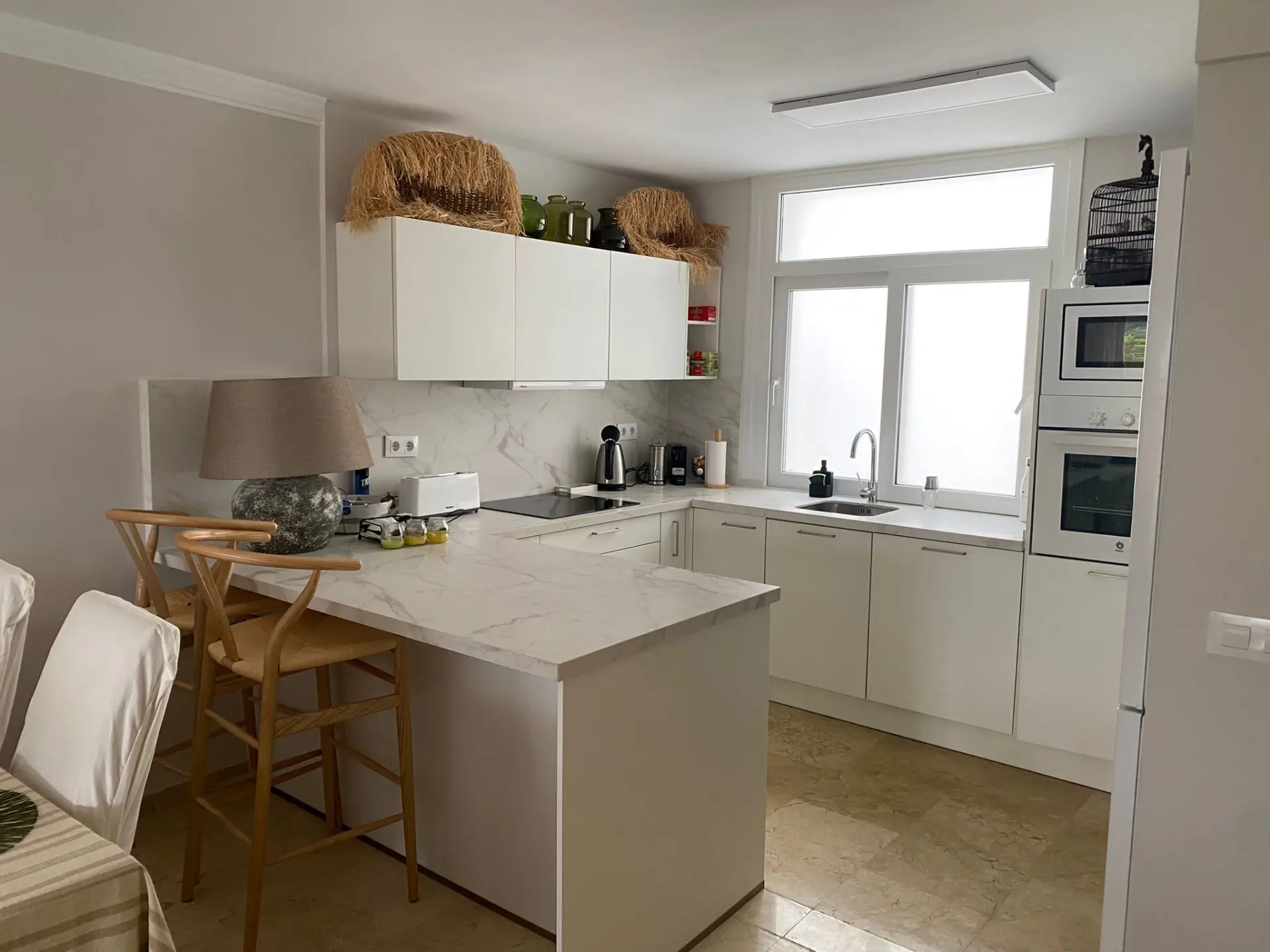 Cocina con muebles blancos y barra de desayuno