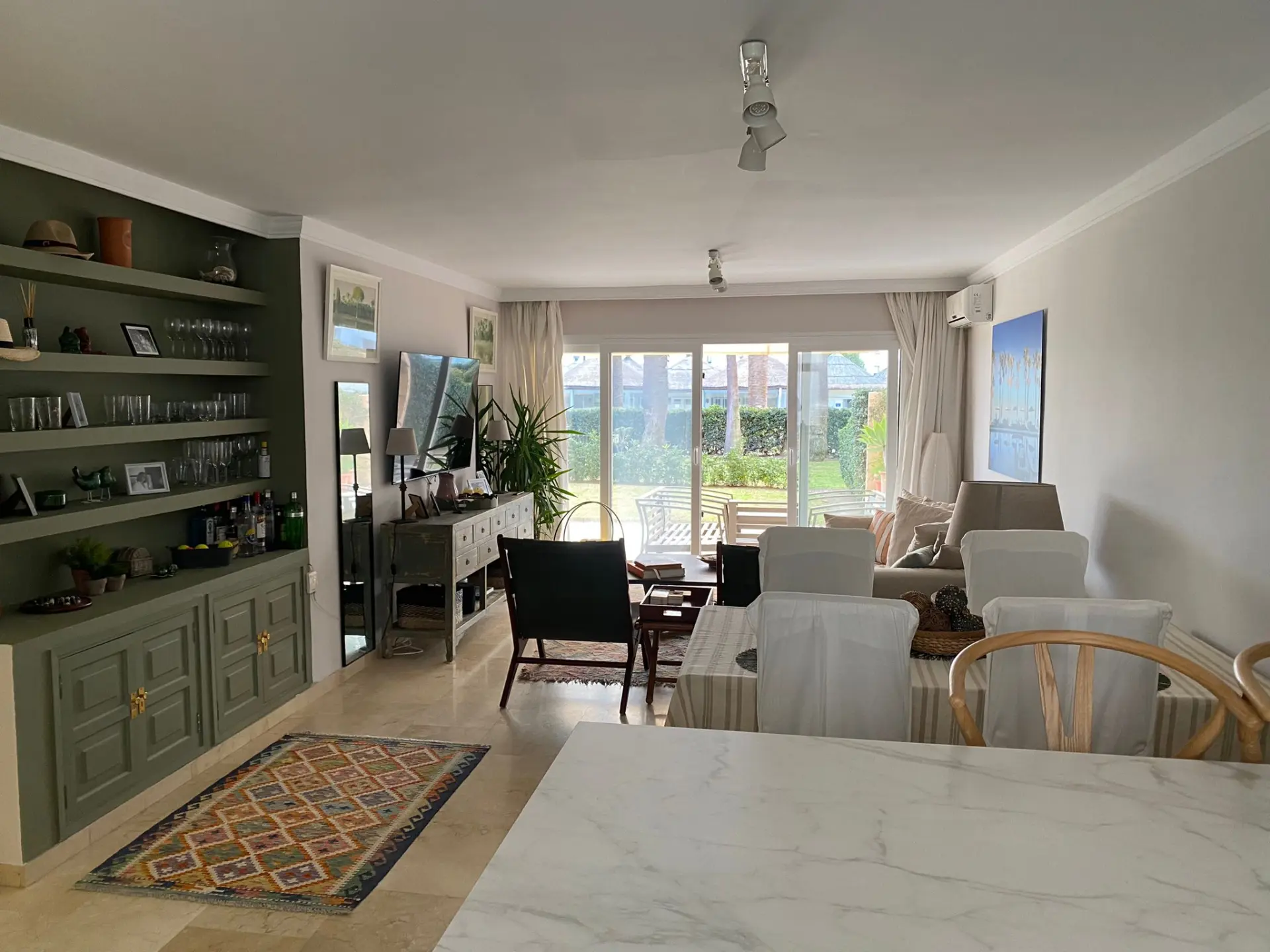 Salón con sofás, estanterías empotradas y acceso al jardín