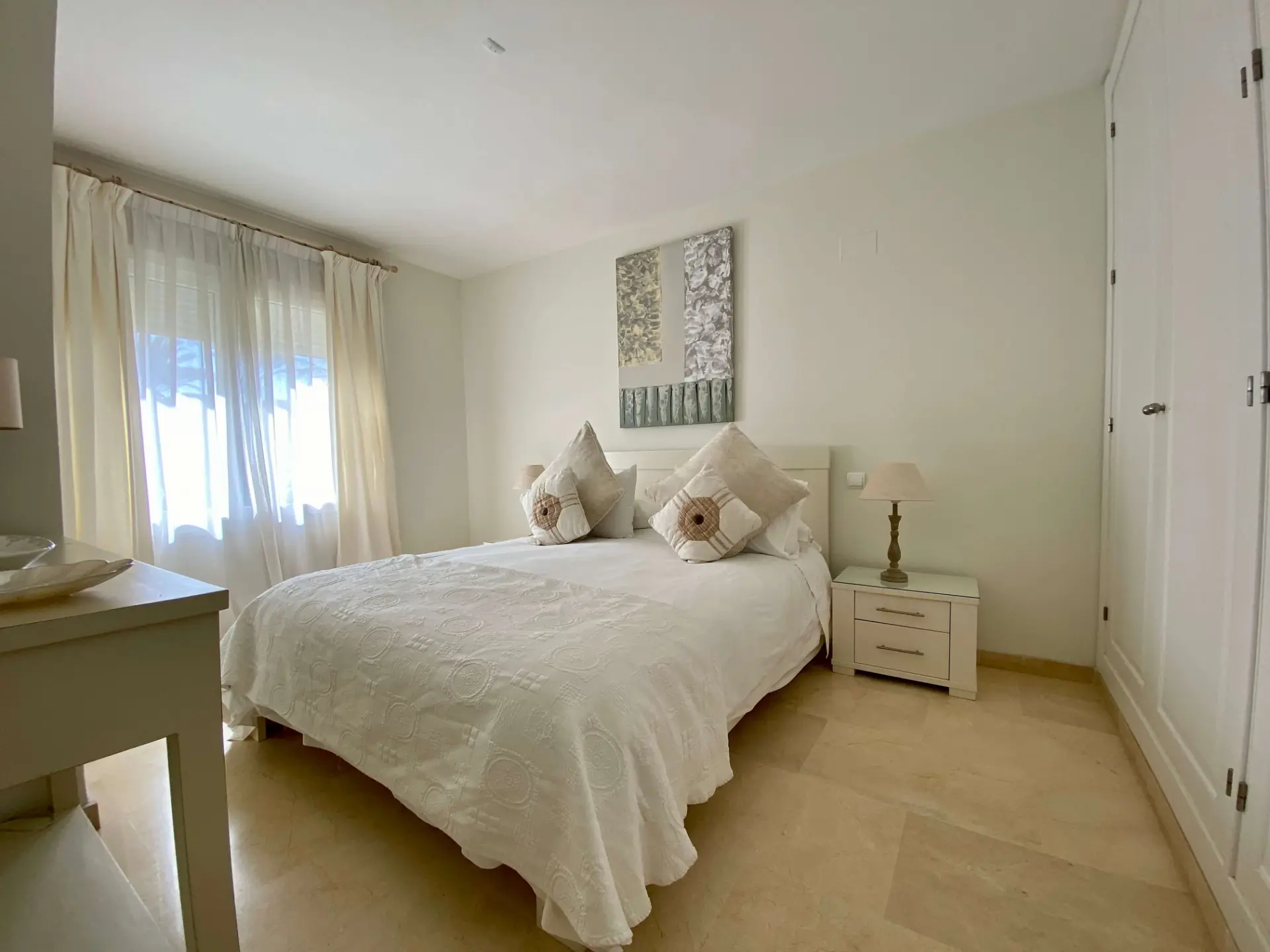 Bedroom with double bed, white wardrobes and soft natural light