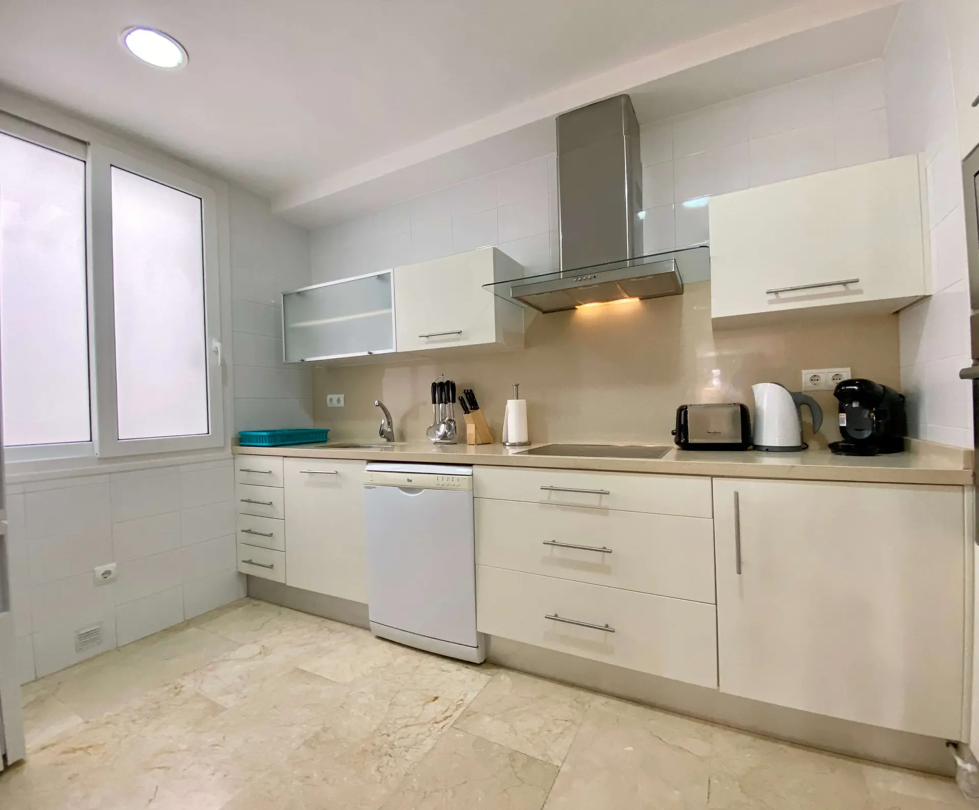 Kitchen with white cabinetry, hob and natural light