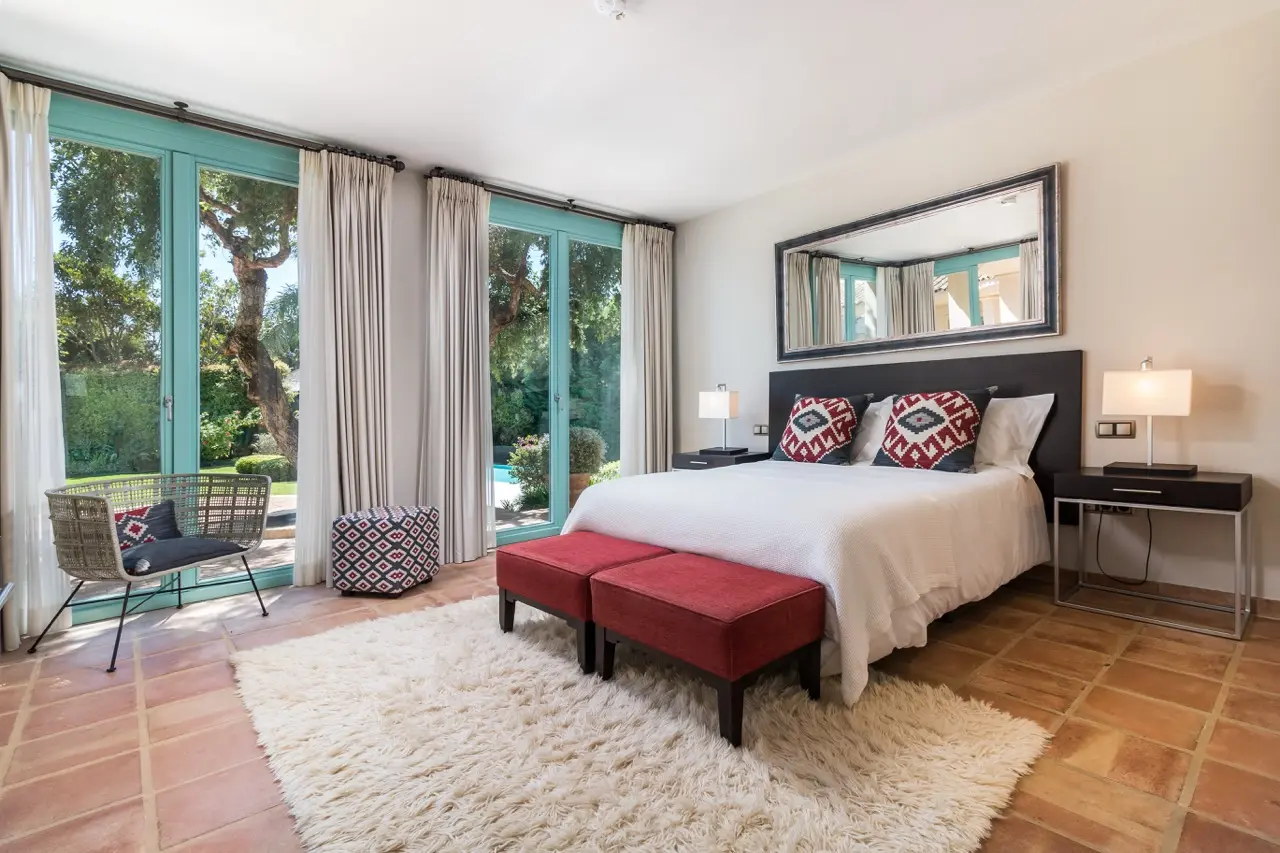 Dormitorio con cama doble, puertas al jardín y suelo de madera