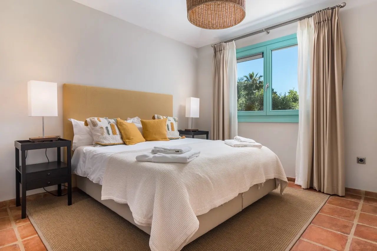 Dormitorio con cama doble, lámparas de noche y ventana al jardín