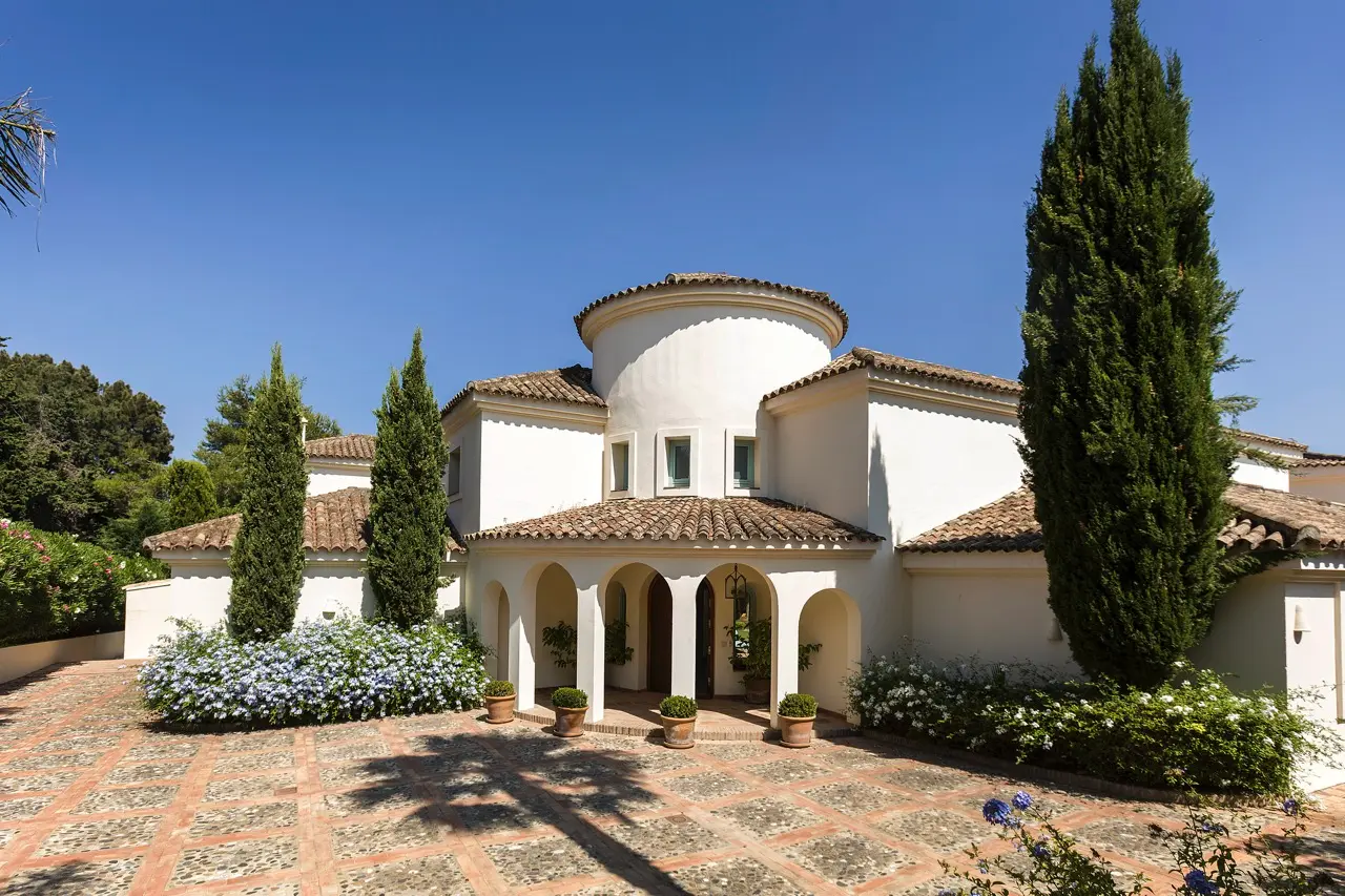 Fachada principal de Casa Azalea con patio, columnas y vegetación madura