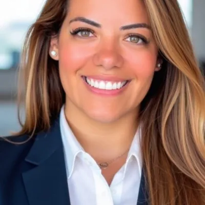 Smiling woman with long brown hair wearing a navy blazer and white shirt.