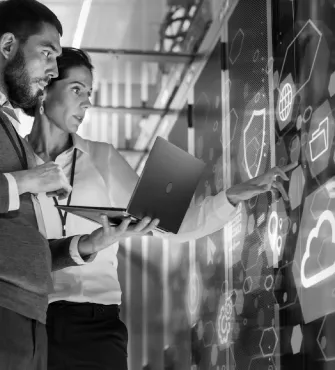 Two professionals interacting with a transparent digital touchscreen displaying icons related to cloud computing and security.