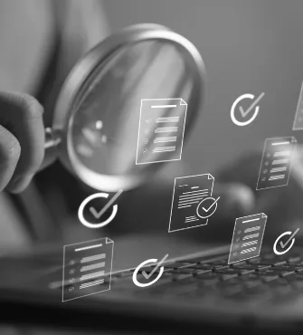 Person holding magnifying glass over laptop keyboard with floating digital icons of documents and checkmarks representing quality control or document verification.