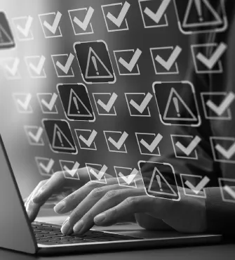 Hands typing on a laptop keyboard with floating check marks and warning icons overlay.