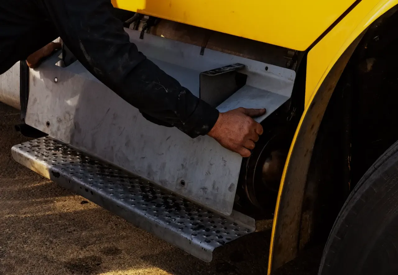 Technician accesses heavy-duty truck DPF compartment for inspection and maintenance.