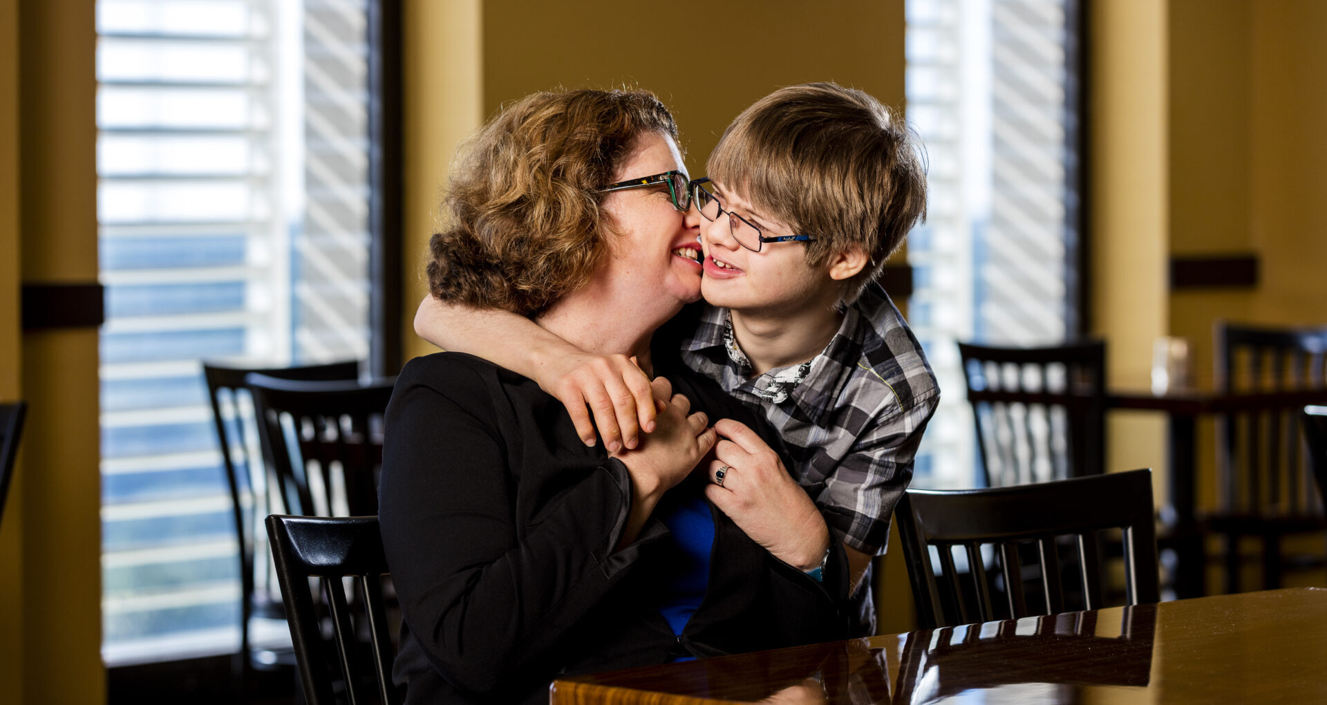 Mom hugging and kissing her disabled son