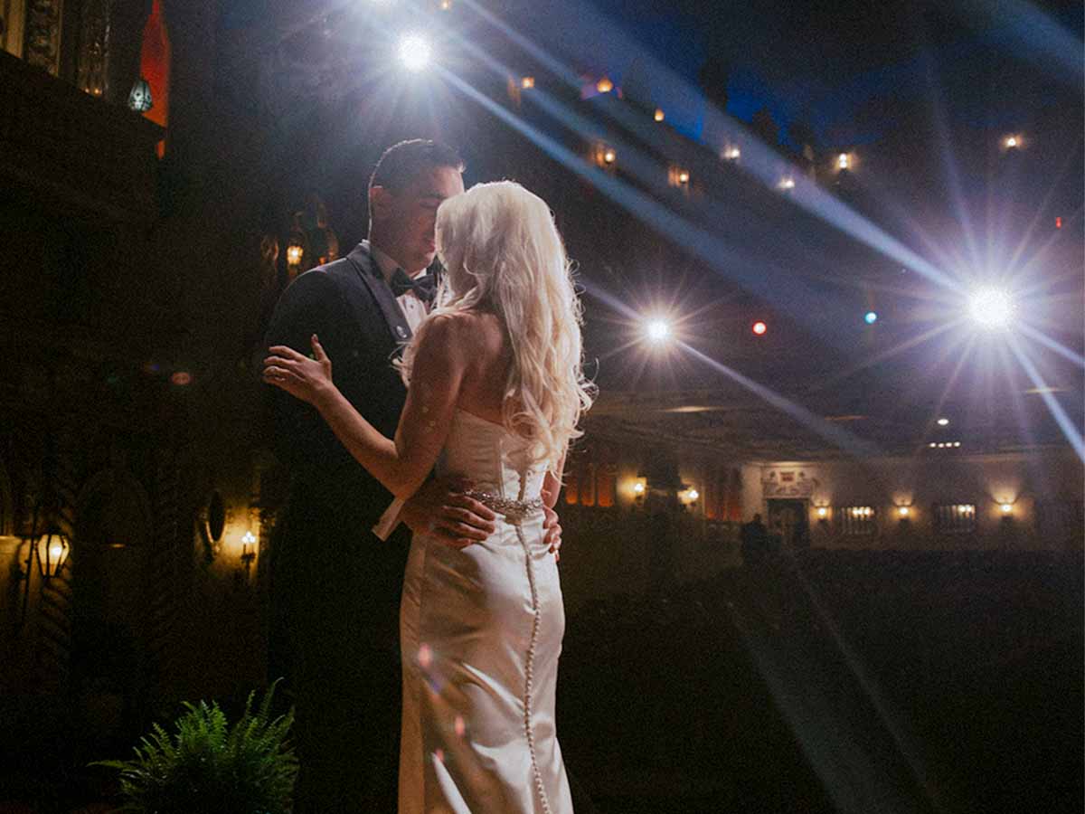 Bride and groom sharing a dance on stage under bright spotlights at The Paramount Theatre.