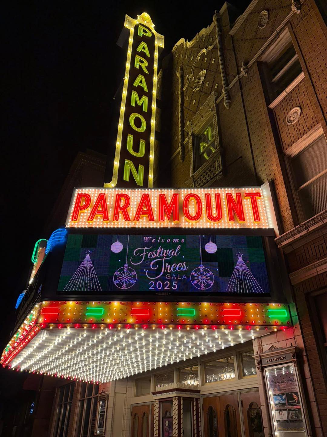 Night view of the Paramount theater marquee lit with colorful lights announcing the Festival of Trees Gala 2025.