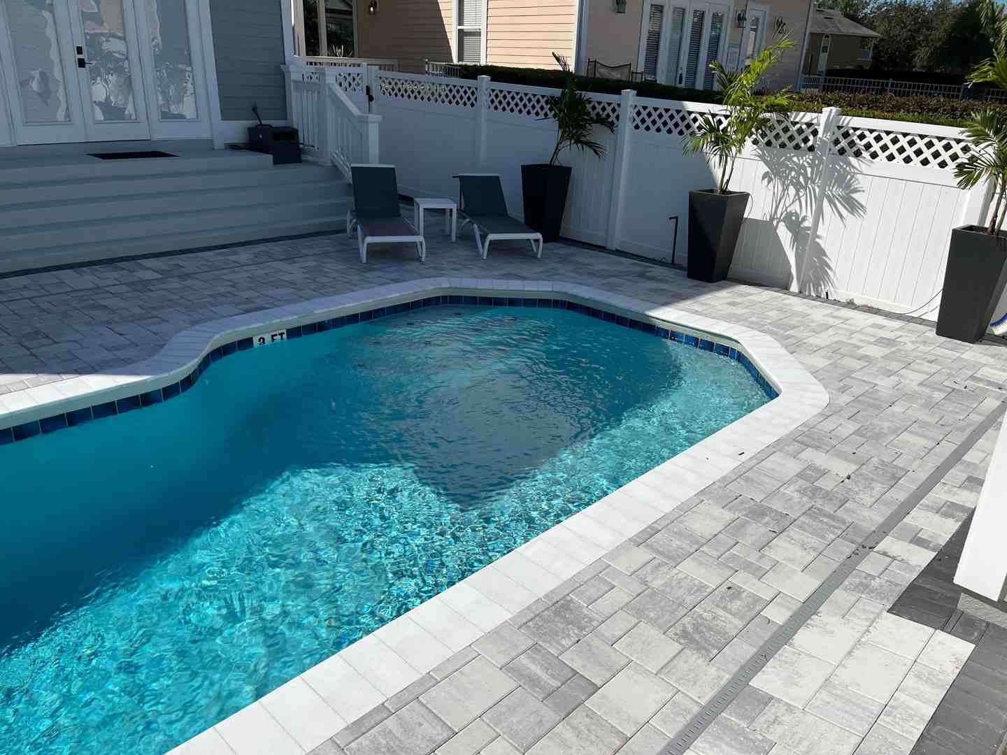 bare feet walking comfortably on light-colored travertine pavers next to a pool on a sunny day - outdoor pool deck stone eustis