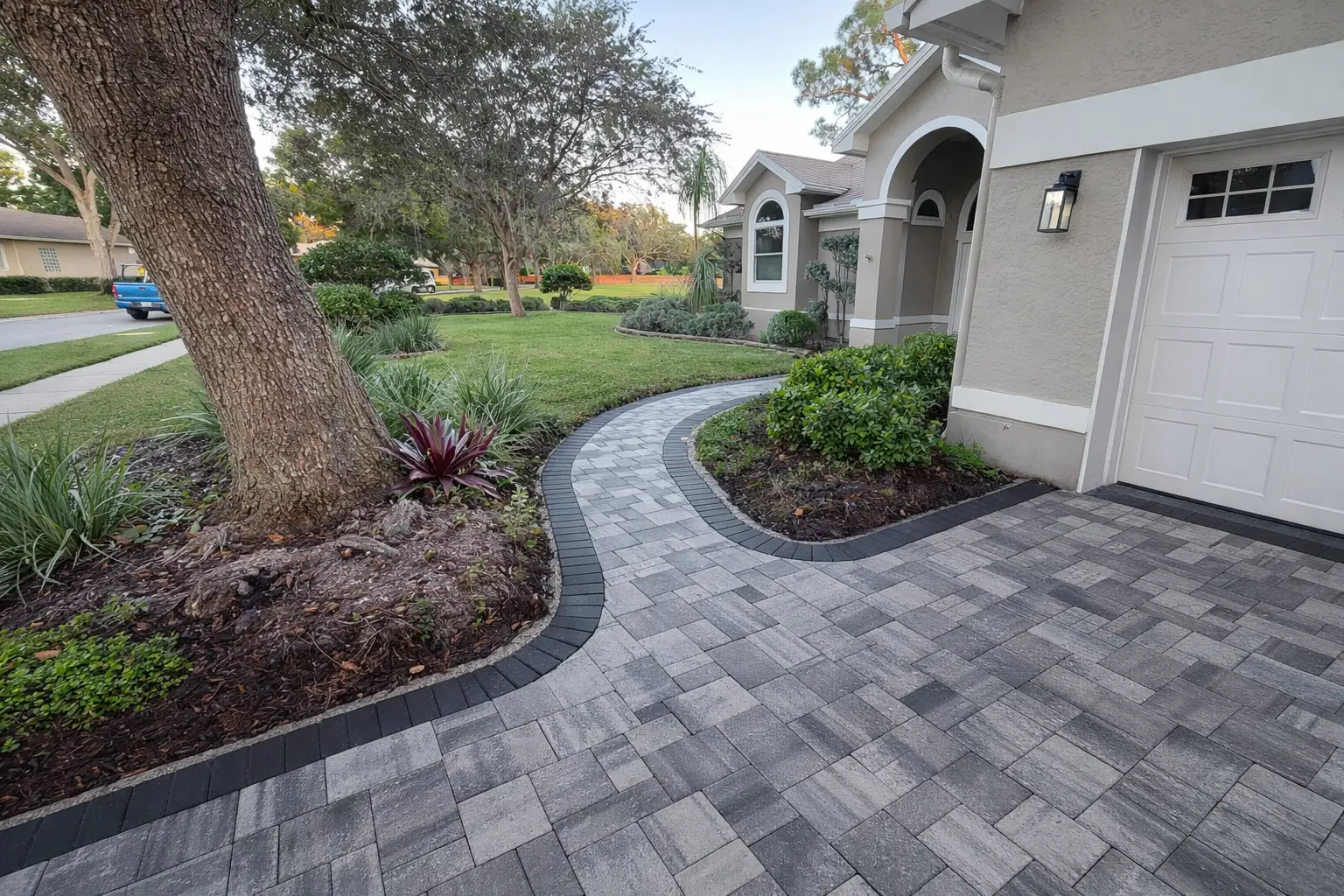 Homeowner using a broom to sweep debris off a clean paver walkway - how to extend the life of your pavers