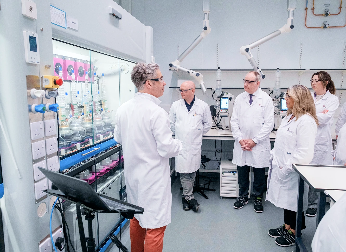CEO Lee Cronin speaking with team members in front of a robotic chemistry platform