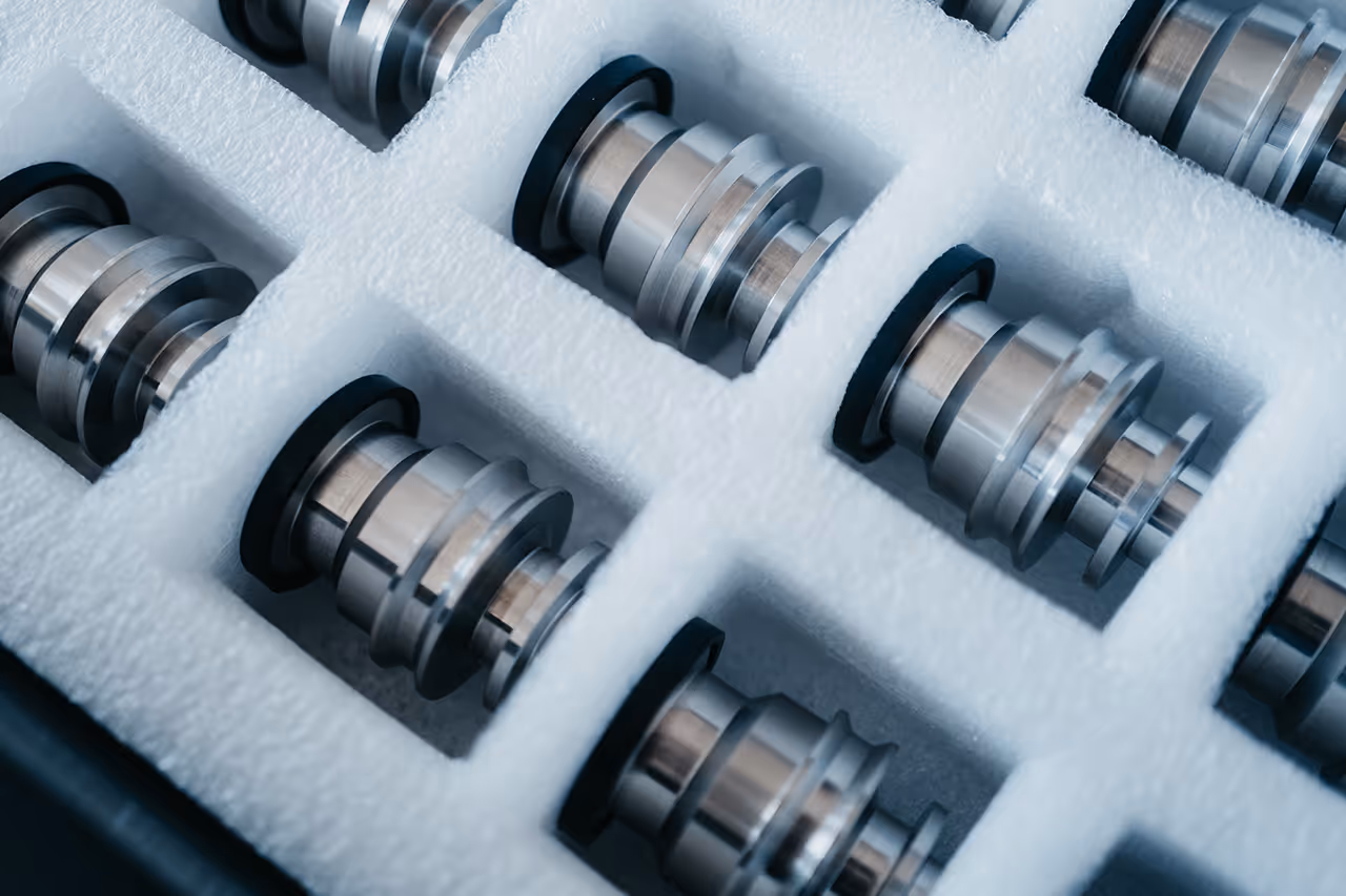 Metallische Maschinenteile ordentlich in weißem Schaumstoffeinsatz verpackt.