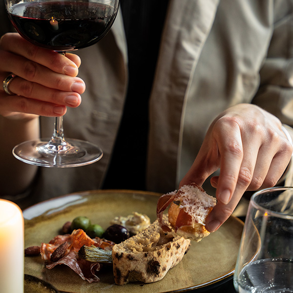 a person having a glass of wine and some small dishes