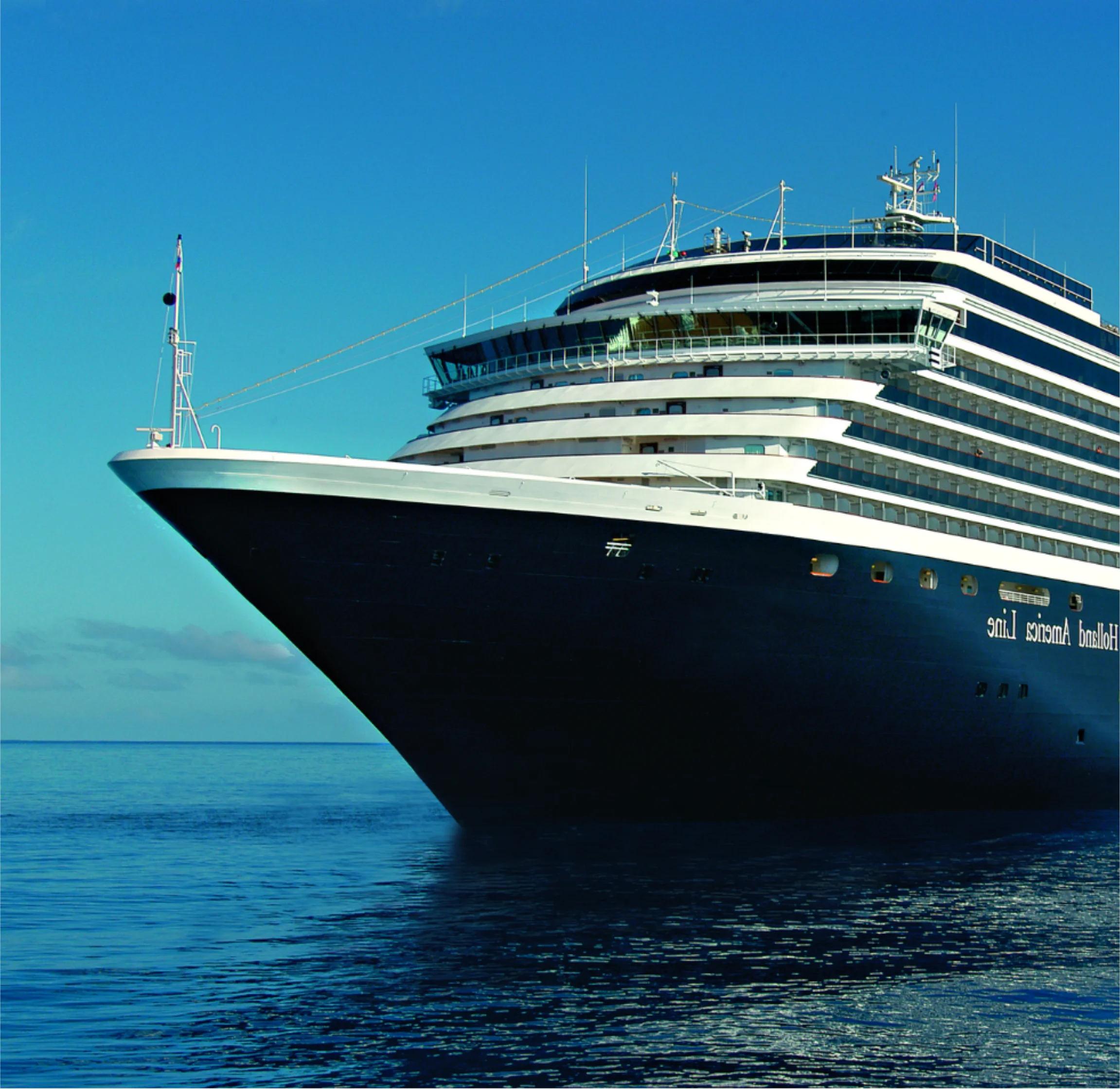 Close-up of the front side of Holland America cruise ship sailing on calm blue water under a clear sky.